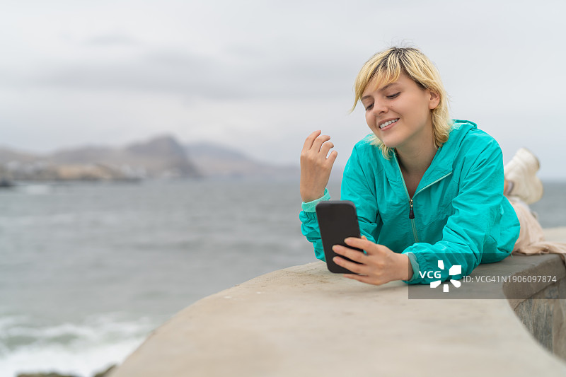 在海滩上使用手机的年轻女人图片素材