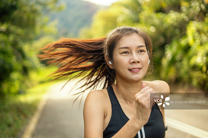 在森林道路上慢跑的运动女人图片素材