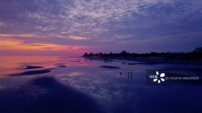 情侣带狗在沙滩上散步图片素材