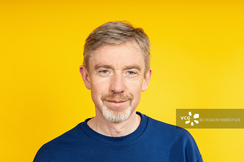 黄色背景上快乐的50岁男人影棚人像照片图片素材