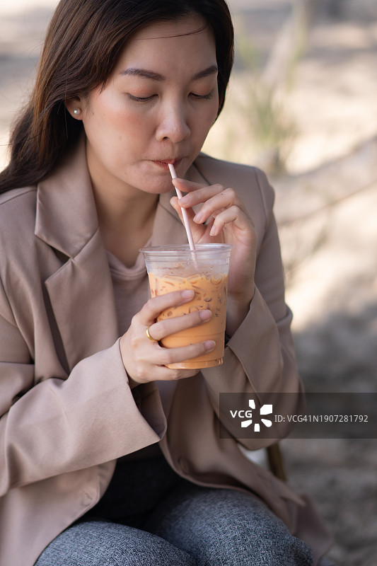 商务装亚洲女人海滨咖啡馆喝泰茶图片素材