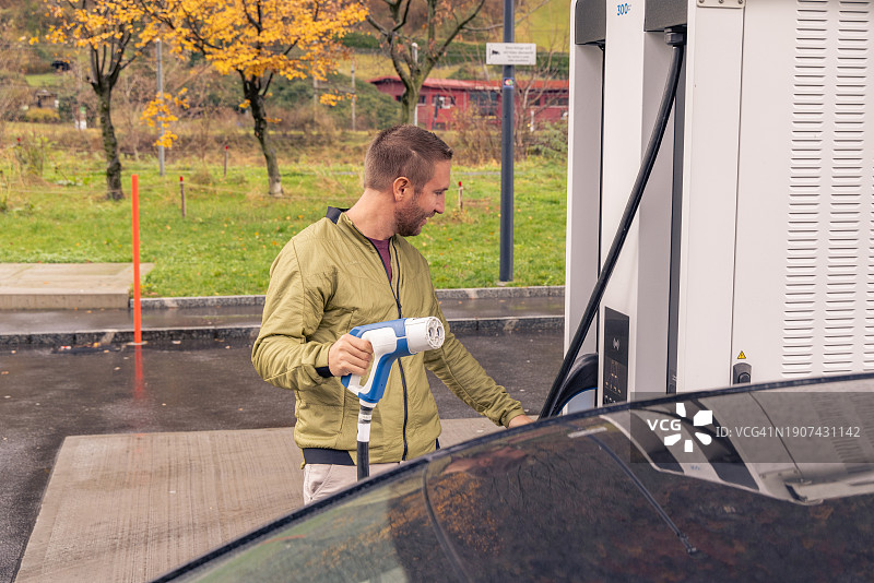 男人在公共充电站给电动汽车充电图片素材