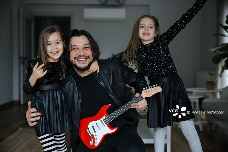 快乐的女儿们在父亲弹吉他时跳舞图片素材