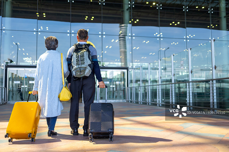 在机场航站楼拖着行李行走的亚洲老年夫妇图片素材