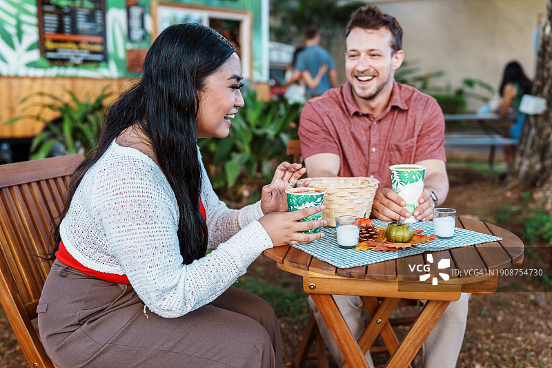 年轻男人和女人在户外餐桌旁吃午餐图片素材