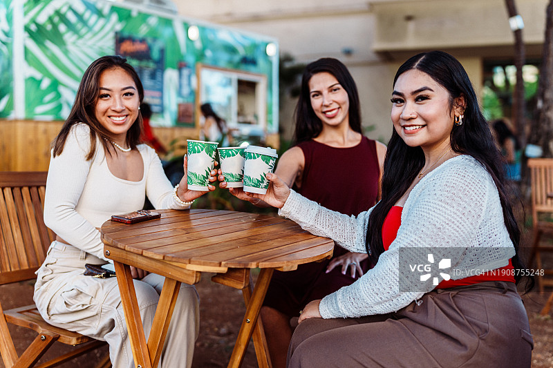 三个年轻女人坐在户外餐桌旁共进午餐图片素材