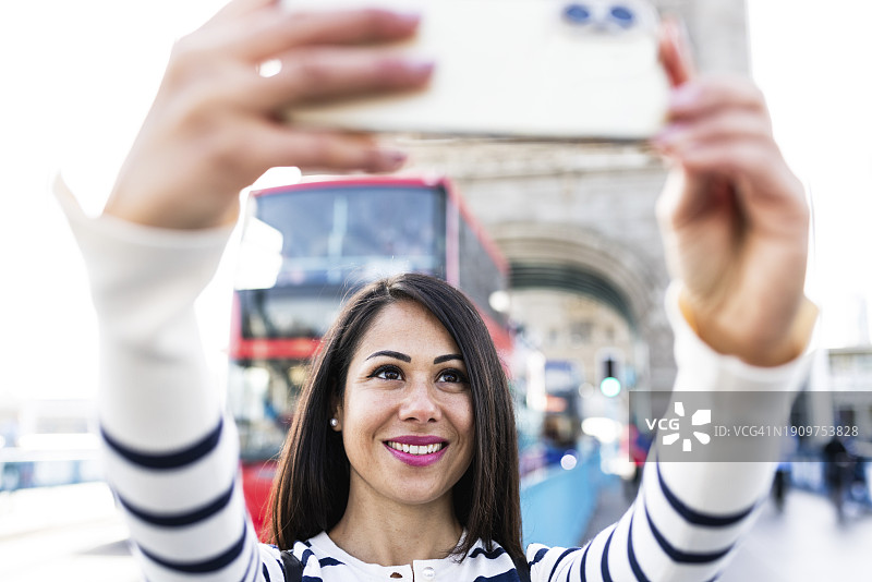 快乐的女人在伦敦用智能手机自拍图片素材