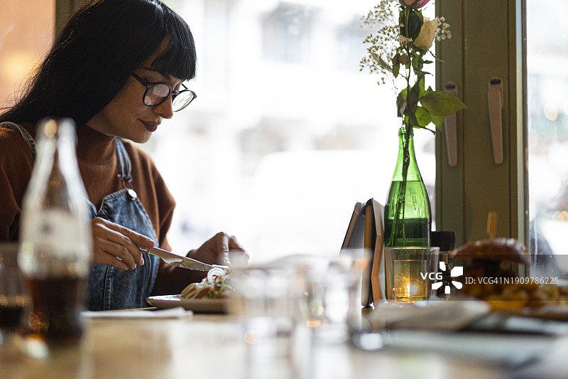 在咖啡馆餐桌旁用餐的女人图片素材