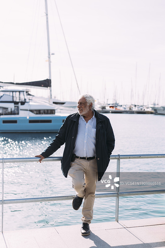 在海港栏杆上沉思的老年男子图片素材