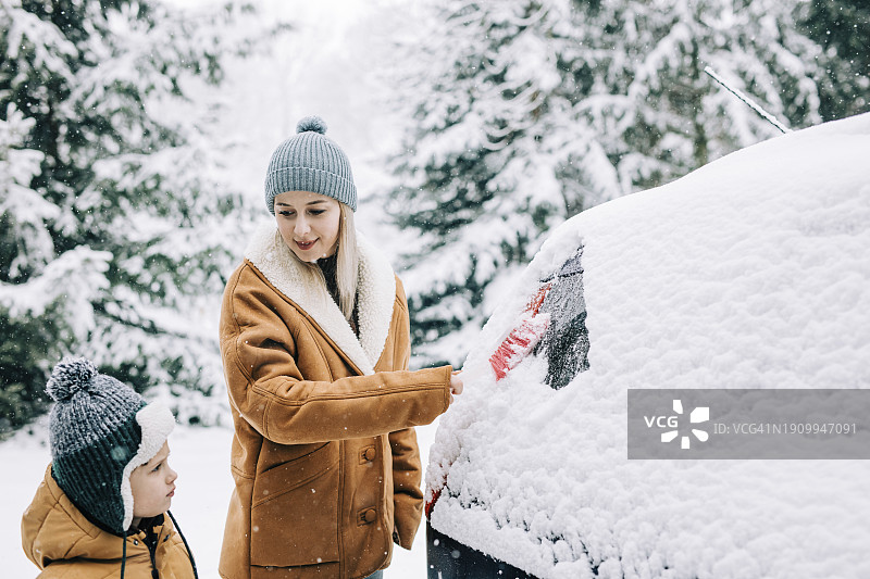 站在儿子旁边，从车上刮雪的女人图片素材