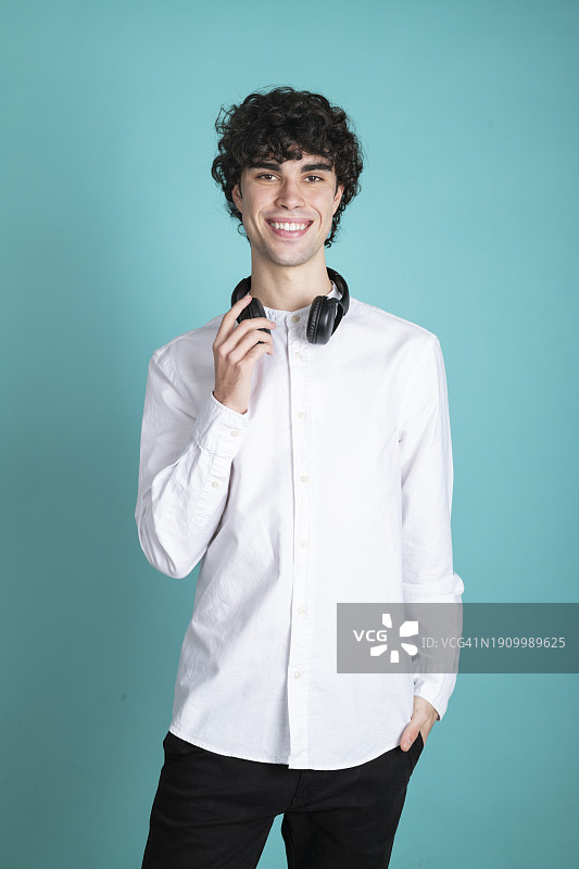 戴着无线耳机，背景为青色的年轻男人图片素材