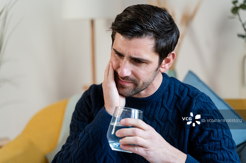 沉思的男人手托脸颊，正遭受牙痛图片素材