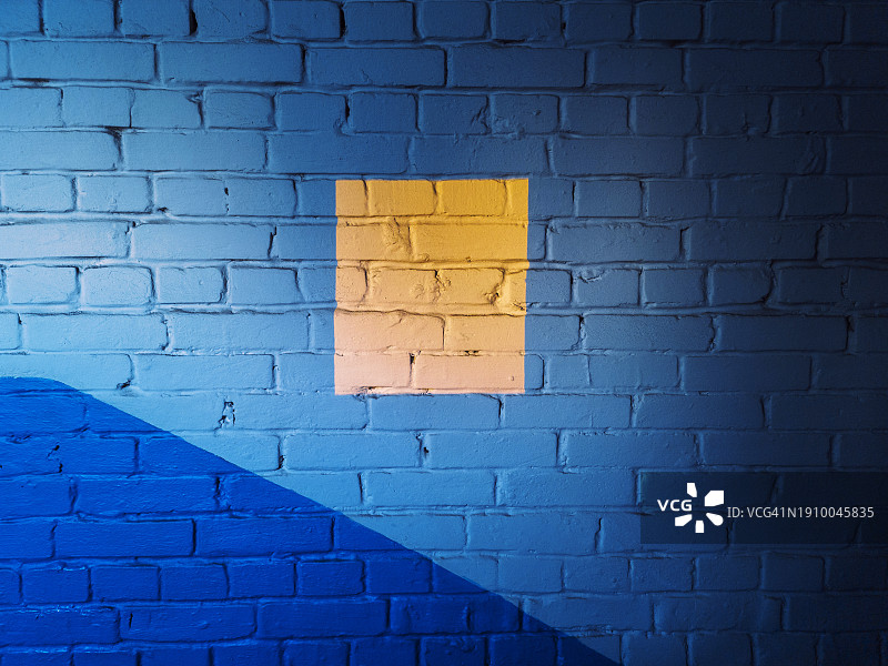 蓝色墙面上黄色正方形光斑，蓝黄撞色对比图片素材