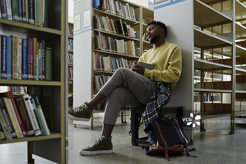 在图书馆书架旁休息的学生图片素材