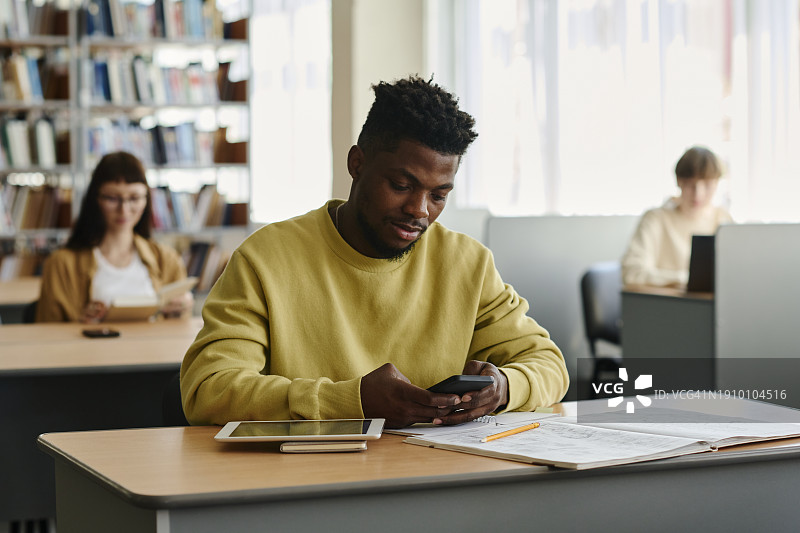 年轻学生在大学图书馆使用智能手机图片素材