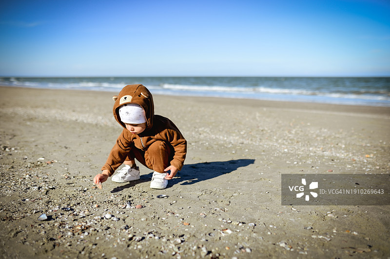 儿童在沙滩上玩沙子和贝壳图片素材