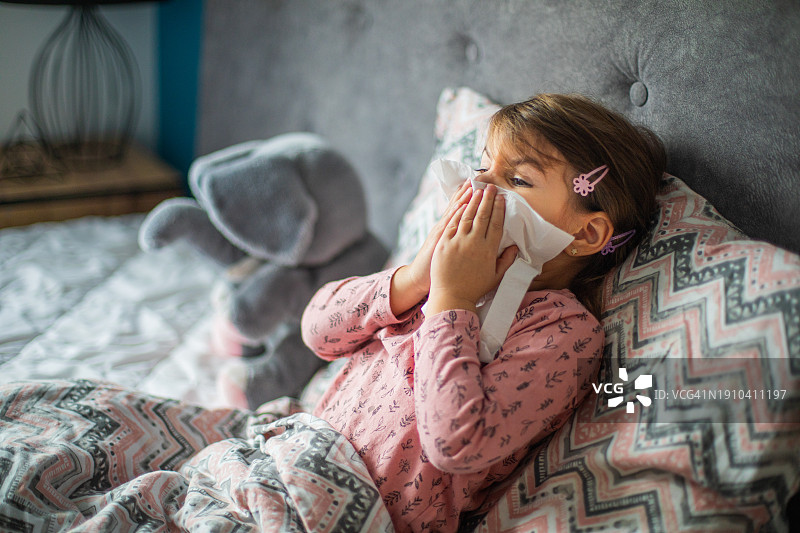 小女孩在卧室里用纸巾擦鼻涕图片素材