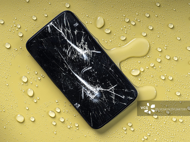 黄色背景上屏幕摔碎且被水浸湿的智能手机图片素材