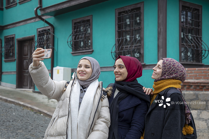 在埃斯基谢希尔历史悠久的奥顿帕扎里房屋前自拍的年轻穆斯林女游客图片素材