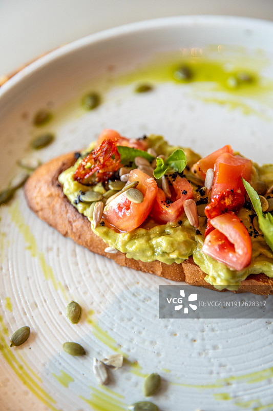 健康的纯素牛油果吐司，配西红柿、香草和种子图片素材