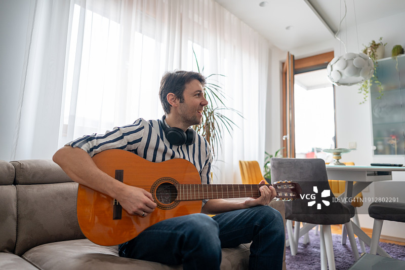 男子在公寓里弹奏原声吉他图片素材