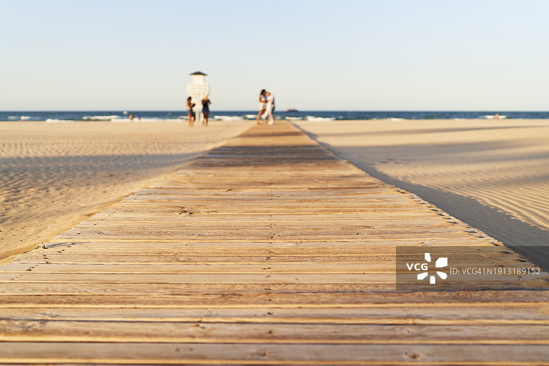 甘迪亚海滩中间的木制小路正面图，背景有人图片素材