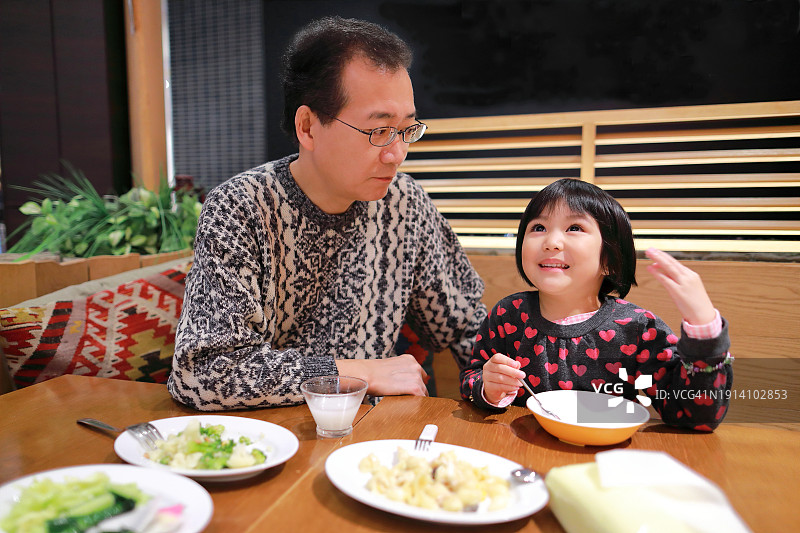 孩子在吃午饭时愉快地和父亲交谈图片素材