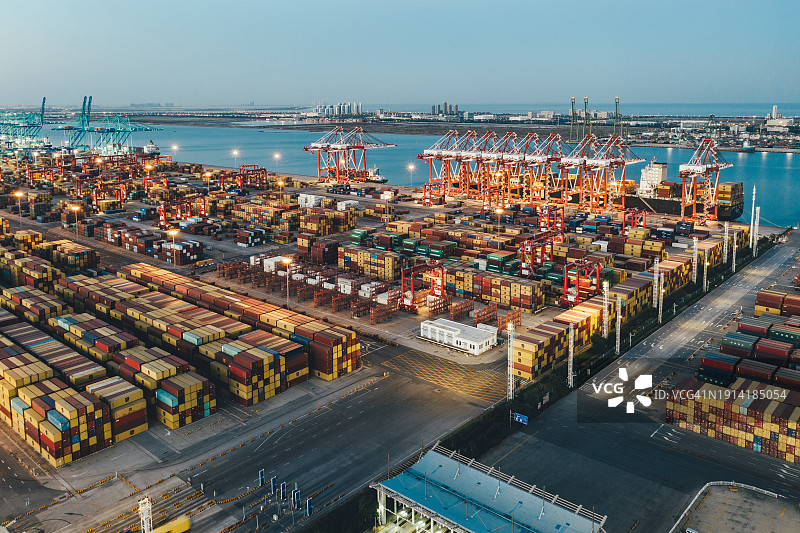 黄昏时分集装箱船的工业港口鸟瞰图图片素材