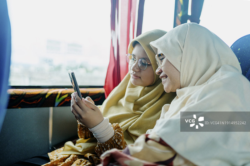 看智能手机屏幕的少女和她的母亲图片素材