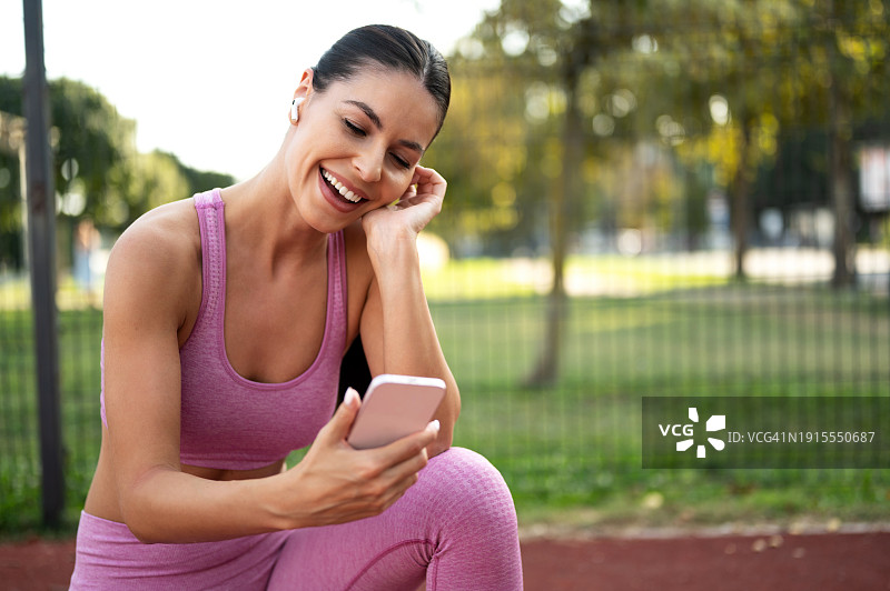 快乐的女运动员在城市公园球场听音乐和锻炼图片素材