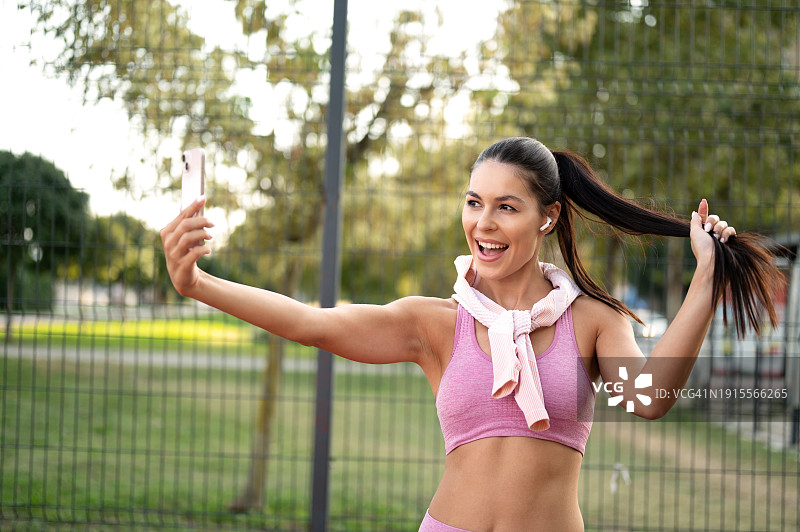 快乐的女运动员在城市公园球场户外锻炼时自拍图片素材