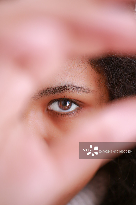 女孩从指缝间看着我。图片素材