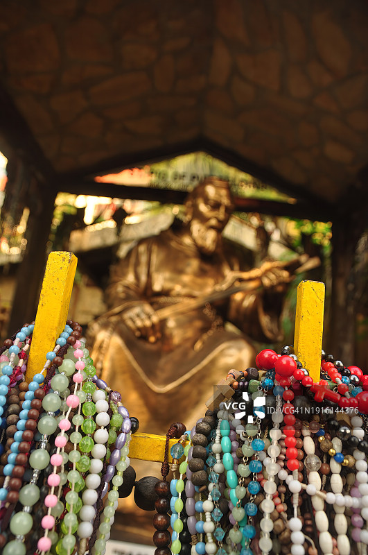 挂在栅栏上的念珠，背景是圣比约神父的青铜雕像图片素材