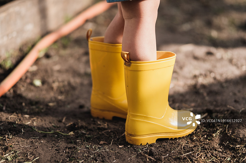 穿着黄色雨靴站在温室里的小孩图片素材