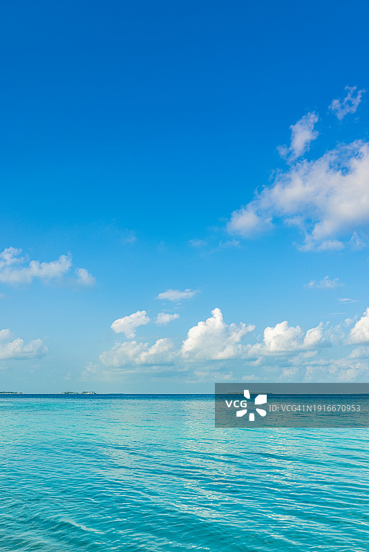 阳光明媚的蓝天碧海，平静的海湾，祥和的海浪，世界环境日概念，令人放松的云彩海景，旅游岛屿海岸，海滩风光，平静的水面地平线图片素材