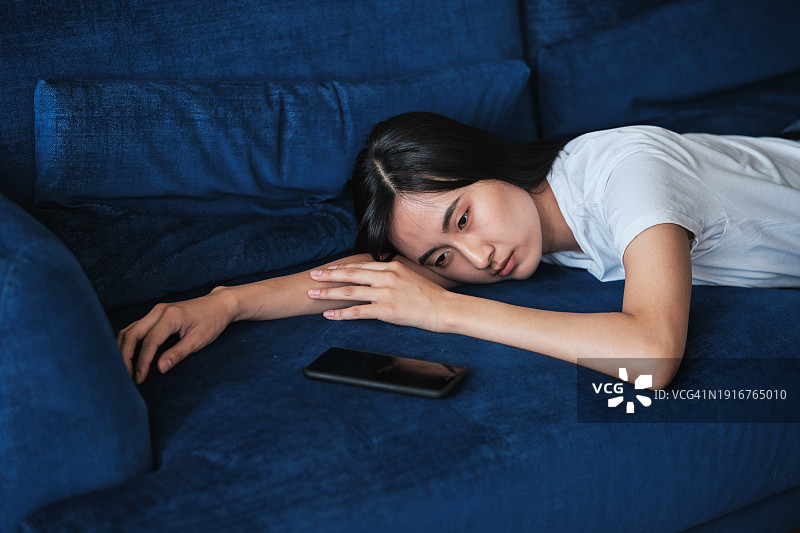 社交媒体与抑郁：沮丧的亚洲年轻女人看手机图片素材