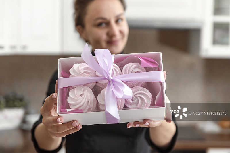 女面包师手拿外卖盒，为顾客配送订单。面包师在厨房烘烤糕点和蛋糕。小企业主和食品配送概念图片素材