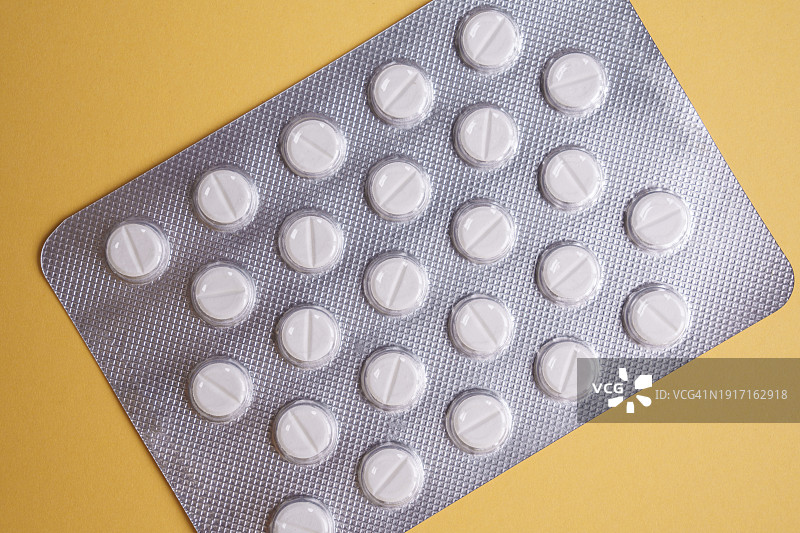 黄色背景上隔离的泡罩包装药片图片素材