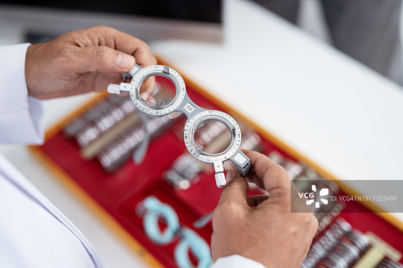 眼科医生使用视力测试仪保持眼睛健康，眼科诊所的验光师手持镜框和镜片图片素材