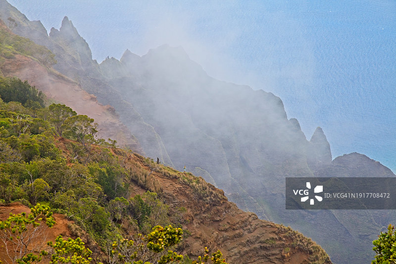 在考艾岛卡拉劳山谷瞭望小径山脊上看到的女登山者，云雾缭绕图片素材