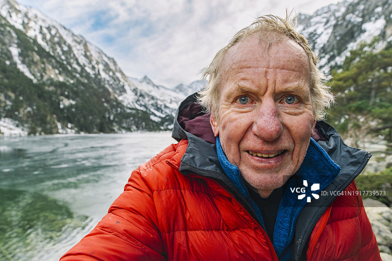 一位老年人在法国比利牛斯山脉的湖光山色前自拍图片素材