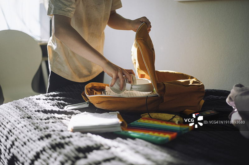 男孩在家将耳机放在书包里图片素材