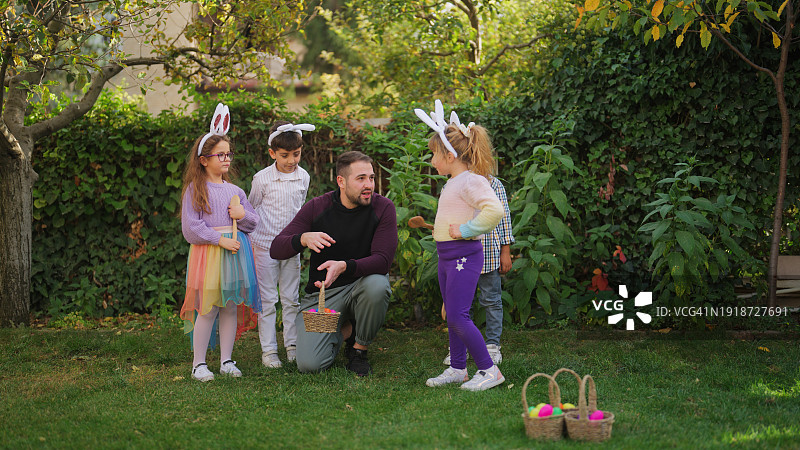 年轻男子向一群在户外玩耍的儿童讲解鸡蛋竞走比赛图片素材