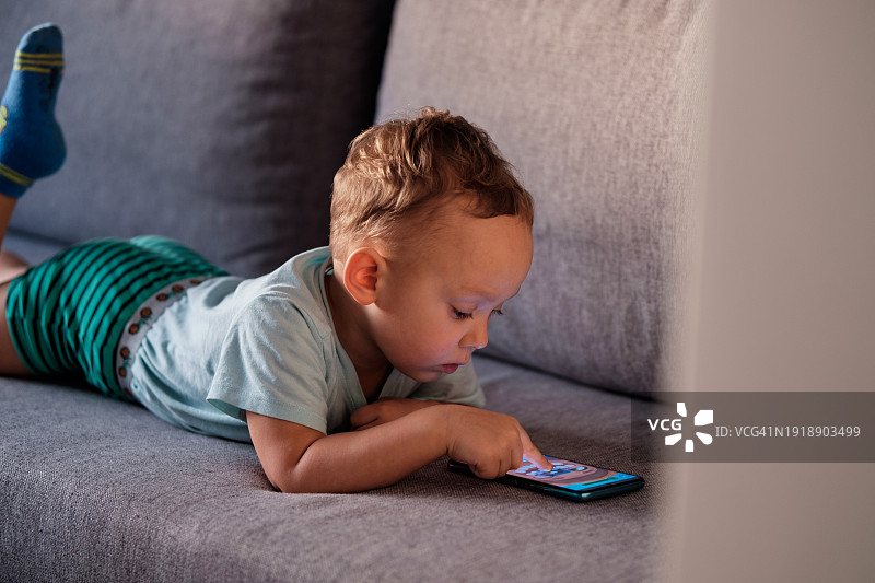 小男孩玩手机游戏，儿童使用智能手机触摸屏幕图片素材