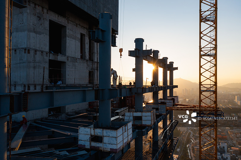 建筑工人在黄昏时建造摩天大楼图片素材