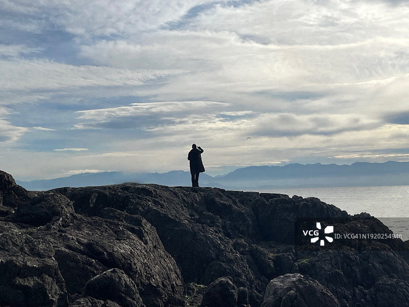 女子站在岩石上眺望大海的背影轮廓，加拿大不列颠哥伦比亚省维多利亚图片素材