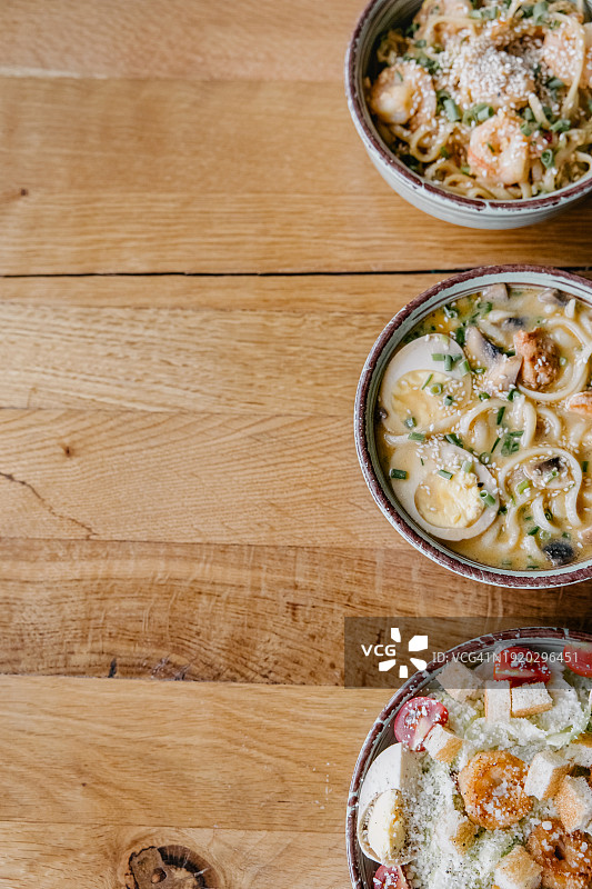 木桌背景上的留白空间：三盘汤和沙拉图片素材