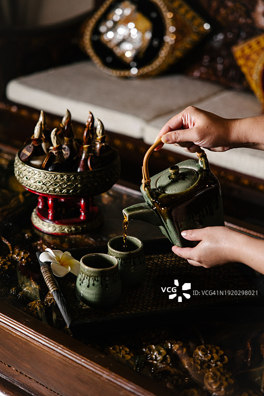 深绿色与棕色调的茶道，女性手持茶壶图片素材