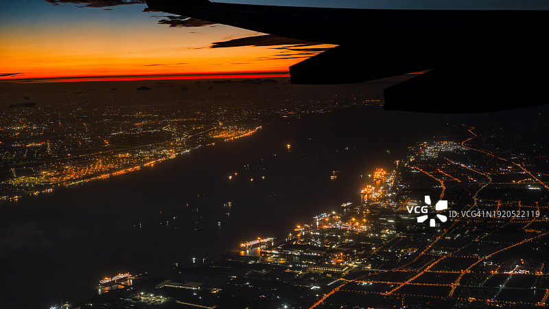 日落时分飞机飞越城市的鸟瞰图图片素材
