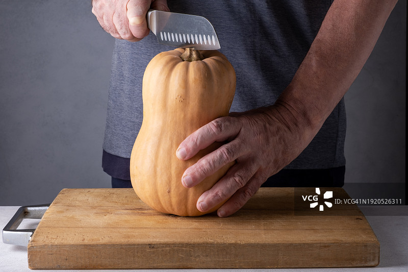 男子在木制砧板上切南瓜（选择性聚焦）图片素材